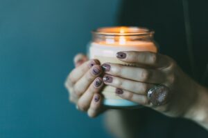 Foto de uma mulher segurando uma vela aromática acessa nas mãos.